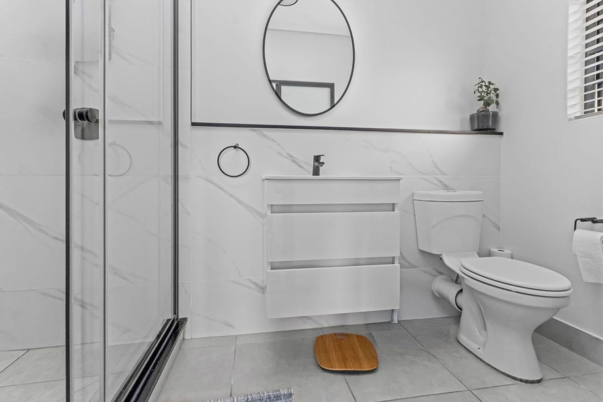 Modern bathroom featuring a glass shower enclosure, sleek vanity cabinet, and contemporary marble-look wall tiling.