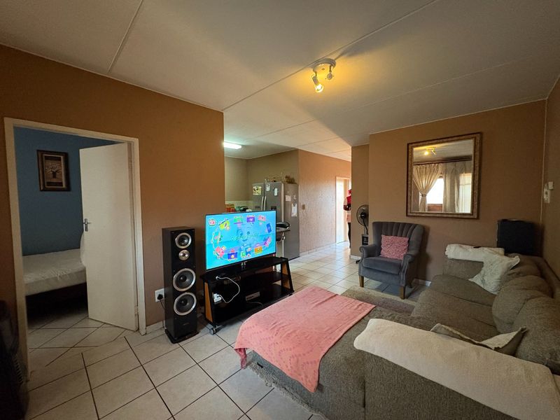 Open plan living area featuring tiled flooring and neutral wall tones, providing a functional layout with direct access to adjacent rooms.