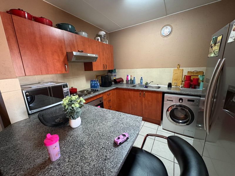 Functional kitchen featuring laminate cabinetry, granite countertops, tiled backsplash, and integrated appliances including a washing machine and built-in oven.