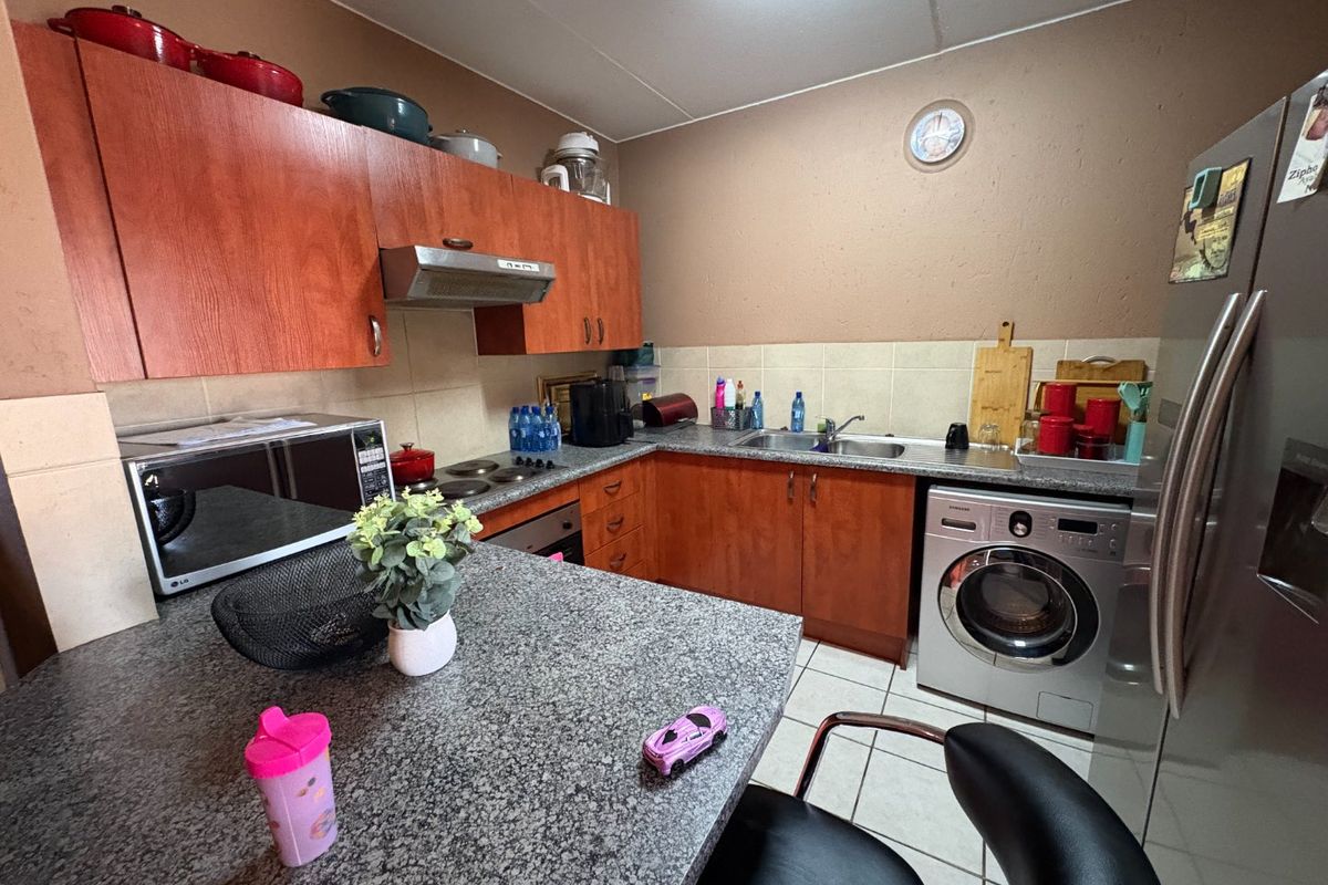 A functional kitchen featuring laminate cabinetry, granite countertops, a tiled backsplash, and integrated appliances including an oven, hob, and washing machine.