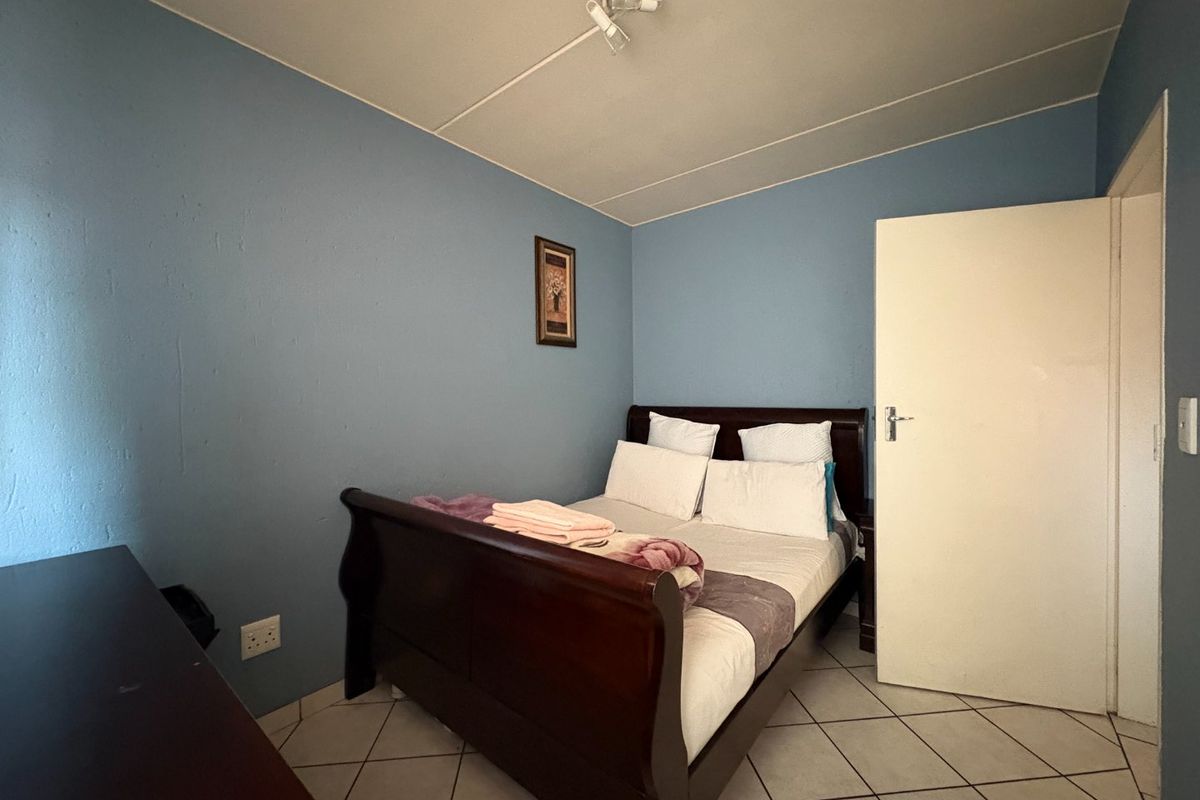 A bedroom featuring tiled flooring and blue painted walls, providing a functional sleeping space within the apartment.