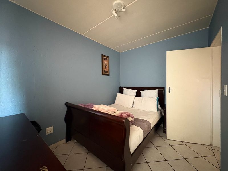 A bedroom featuring tiled flooring and blue painted walls, providing a functional sleeping space within the apartment.