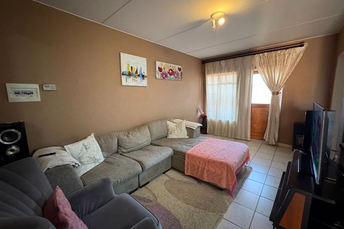 A living room featuring tiled flooring and access to an outdoor area through a glass door.