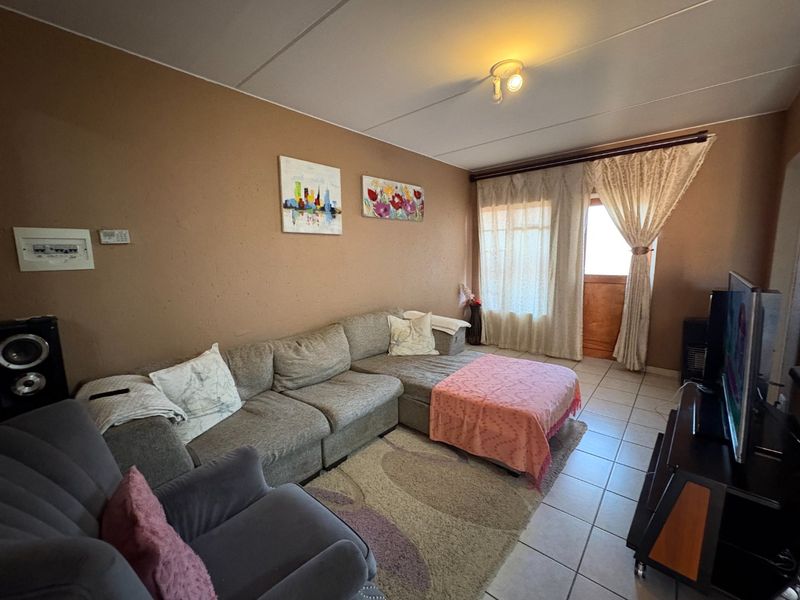 A living room featuring tiled flooring and access to an outdoor area through a glass door.