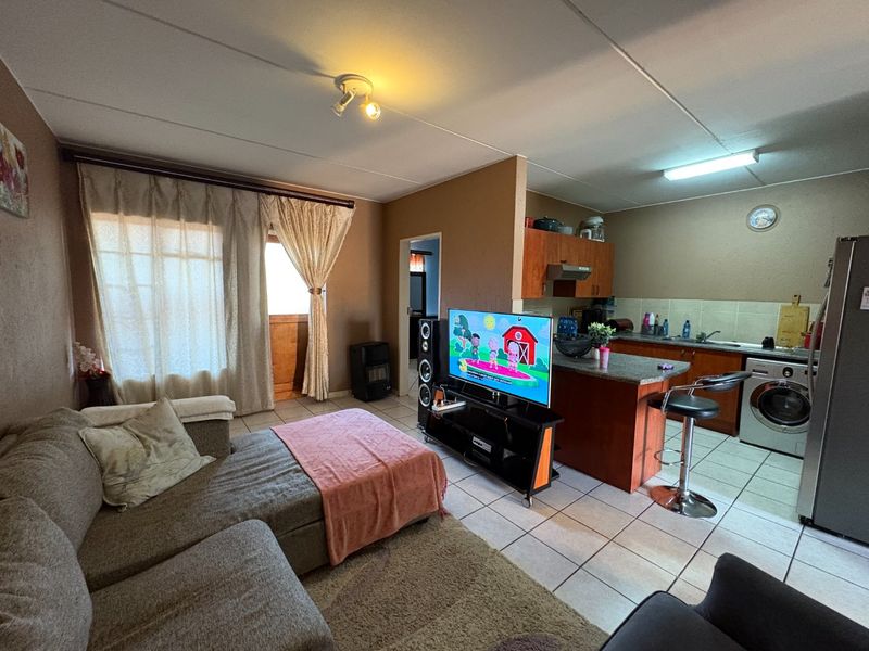 Open-plan living area featuring a combined kitchen with granite countertops and tiled flooring, seamlessly flowing into the adjacent lounge space.