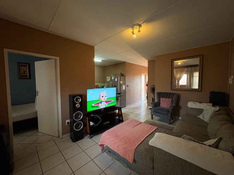 Open plan living area featuring tiled flooring and neutral wall tones, providing a functional space that connects to the kitchen and bedroom areas.