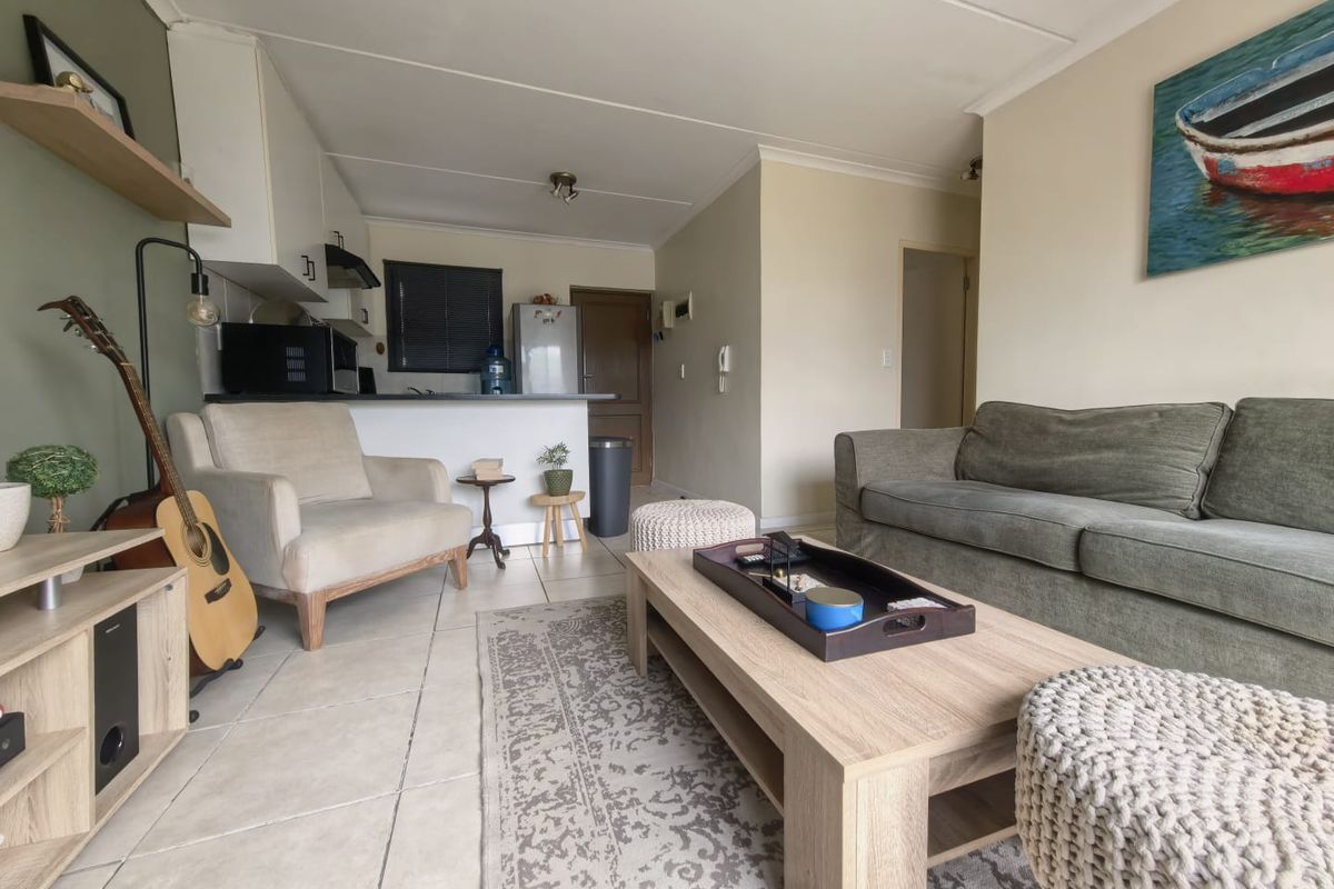Open-plan living area featuring tiled flooring and a functional kitchen space with built-in cabinetry and an extractor fan.