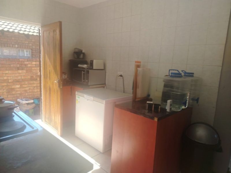 A functional scullery area featuring tiled walls and built-in cabinetry, providing direct access to the exterior.