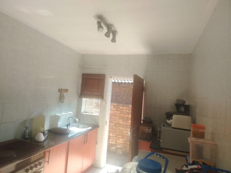 A functional scullery area featuring built-in cabinetry, tiled walls, and direct access to the rear exterior.