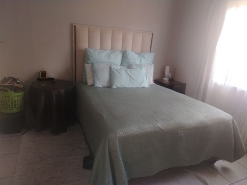 A standard bedroom featuring tiled flooring and natural light from a side window.