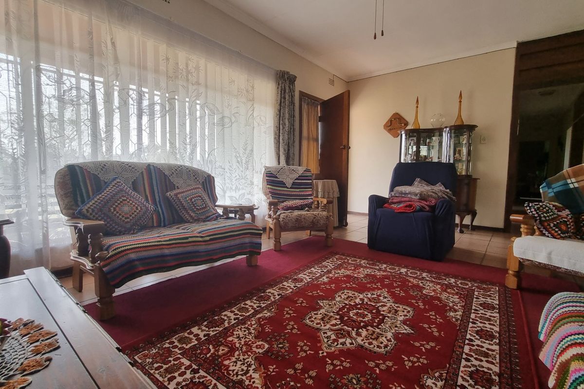 A spacious living room featuring tiled flooring, a ceiling fan, and a large window allowing for natural light.