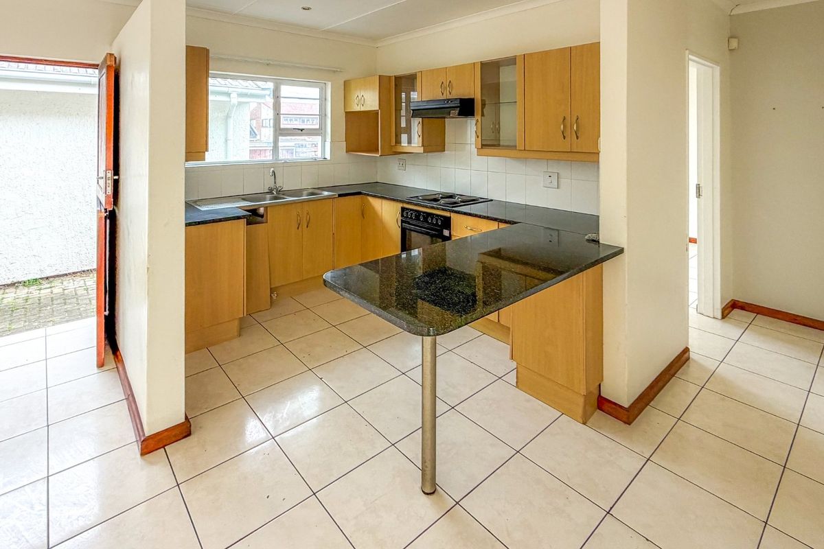 A functional kitchen featuring laminate cabinetry, granite countertops, a breakfast bar, and built-in appliances, with direct access to an outdoor area.