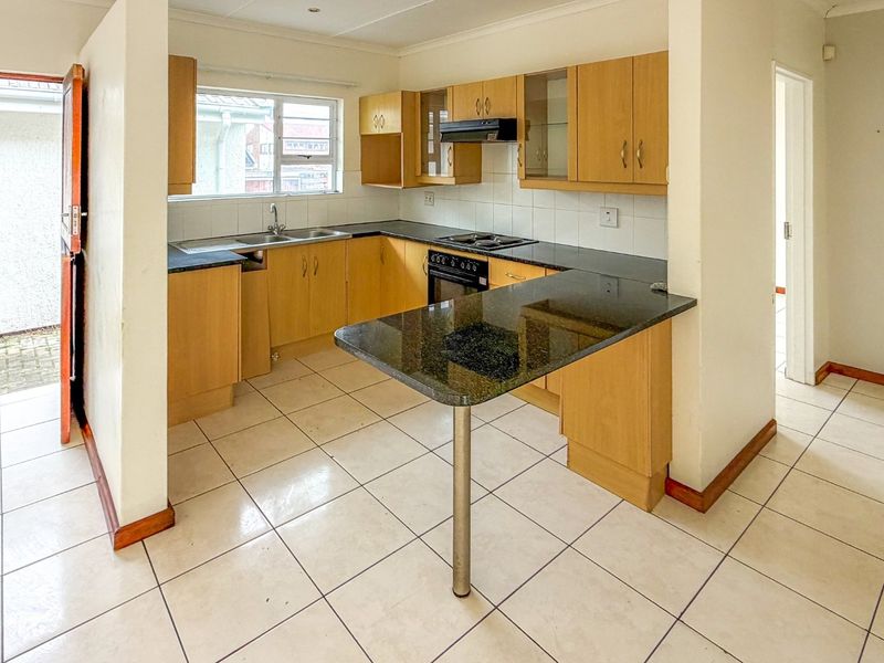 A functional kitchen featuring laminate cabinetry, granite countertops, a breakfast bar, and built-in appliances, with direct access to an outdoor area.