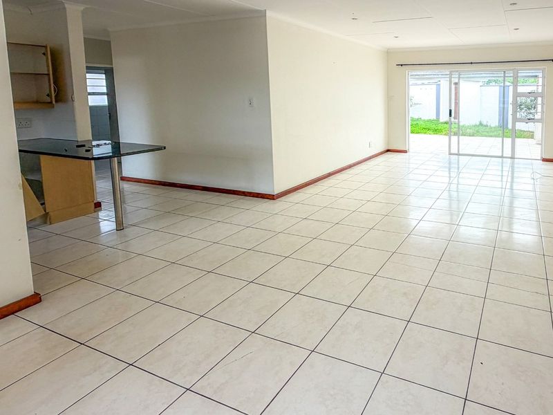 Spacious open-plan living area featuring tiled flooring, a breakfast bar, and sliding glass doors leading to the outdoor space.