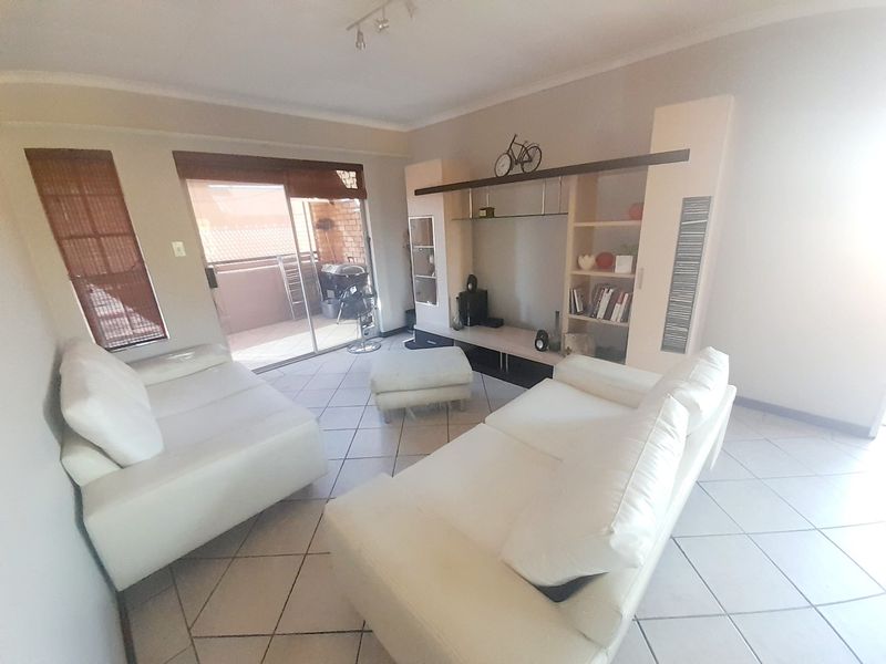 A living room featuring tiled flooring, a built-in shelving unit, and a sliding glass door providing access to an outdoor patio area.