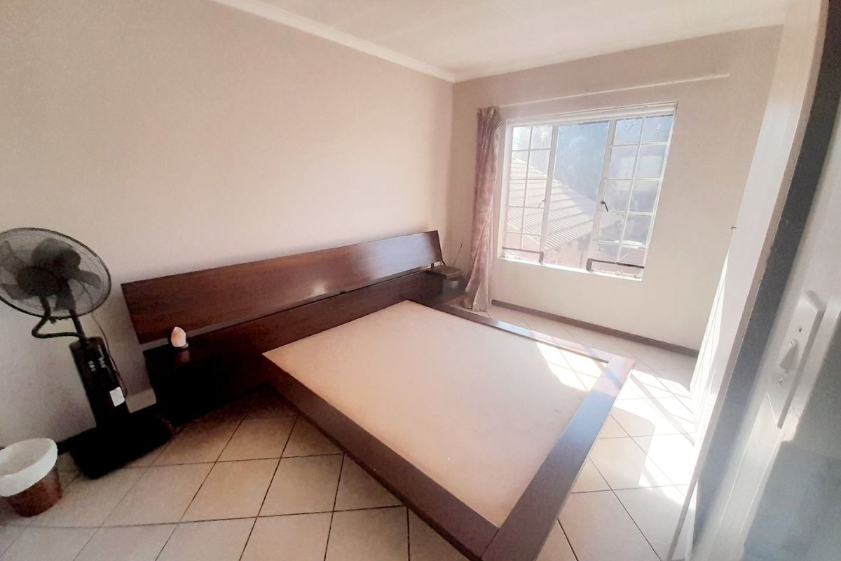 A bedroom featuring tiled flooring, a window with security bars, and cove cornice detailing.