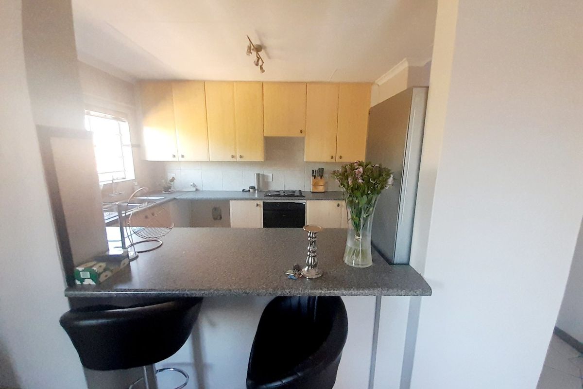 A functional kitchen featuring light-toned cabinetry, laminate countertops, a breakfast bar, and integrated cooking appliances, offering a practical layout for daily use.