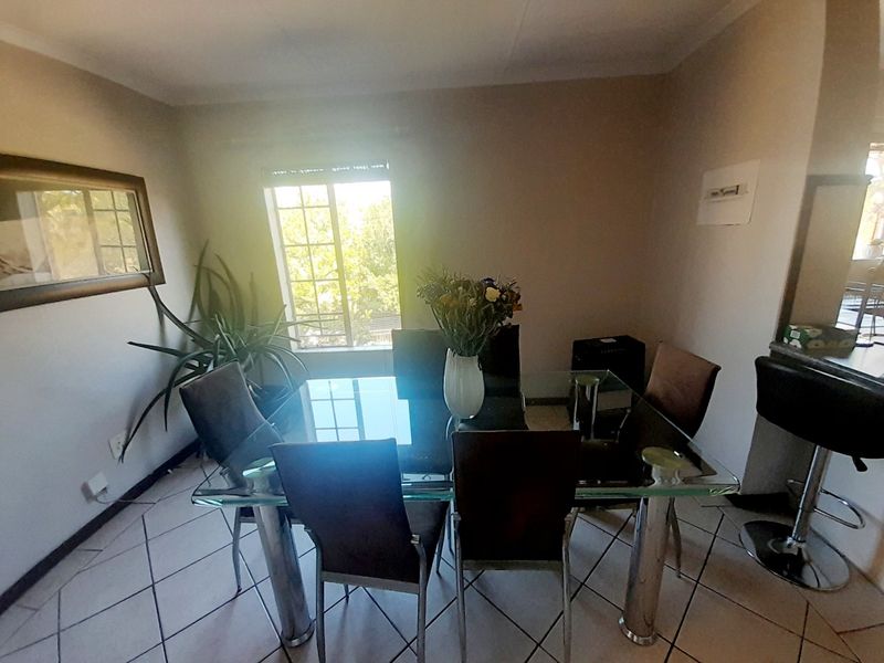 A dining area featuring tiled flooring and a window providing natural light, suitable for family meals and entertaining.