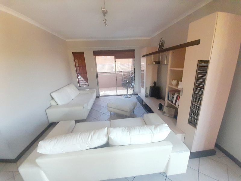 A living room featuring tiled flooring, a built-in shelving unit, and a sliding glass door providing access to an outdoor balcony area.