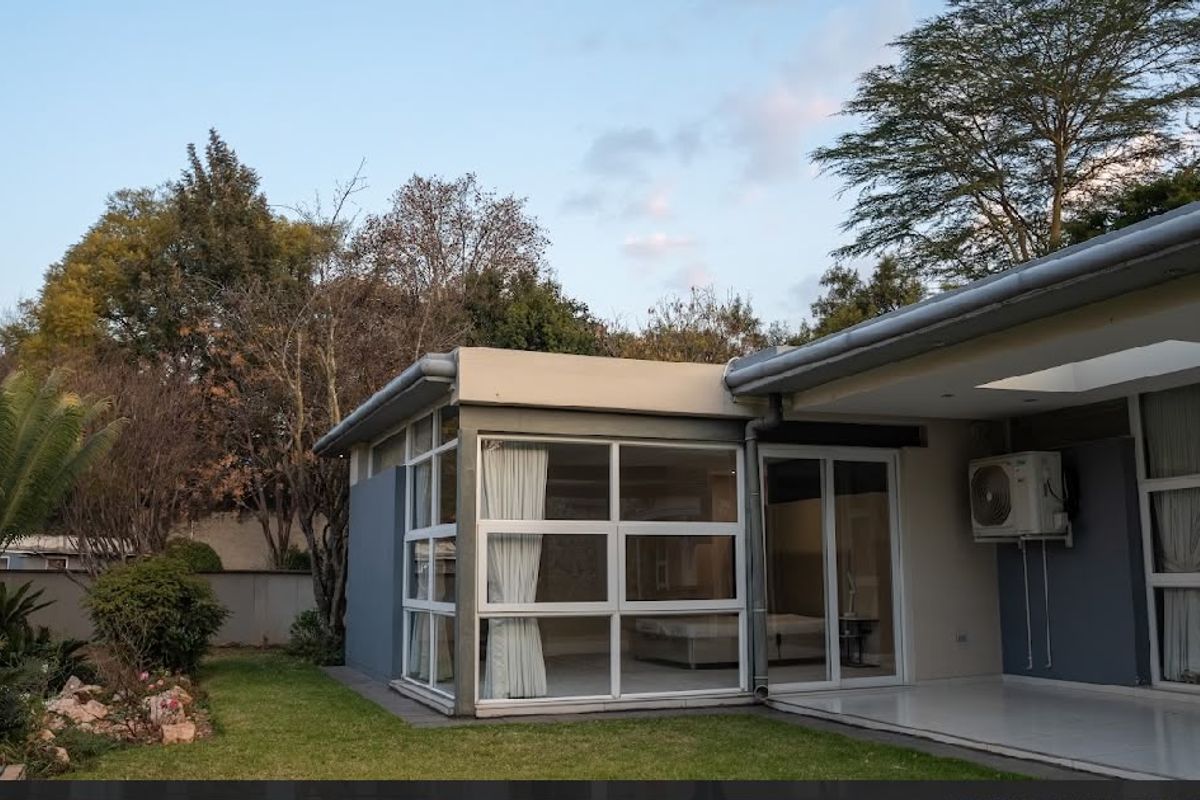 Rear view of the property featuring a covered patio, large glass windows, and sliding doors leading into the interior living space.