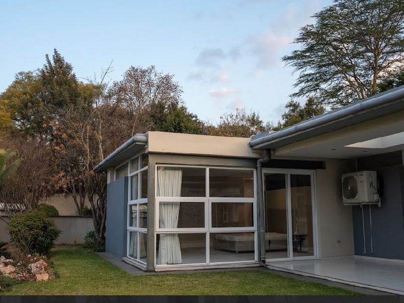 Rear view of the property featuring a covered patio, large glass windows, and sliding doors leading into the interior living space.