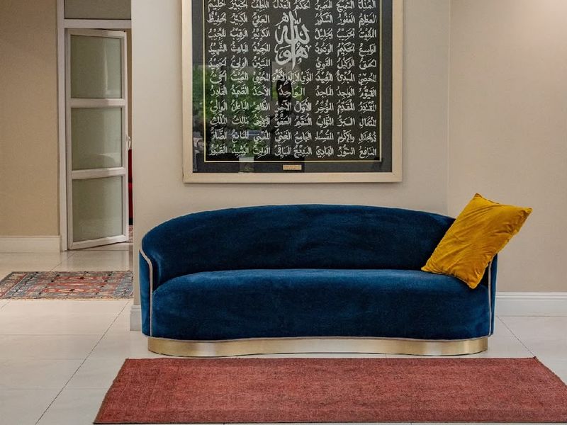 A bright and spacious living area featuring neutral tiled flooring, clean wall finishes, and a glass panel door leading to an adjacent room.