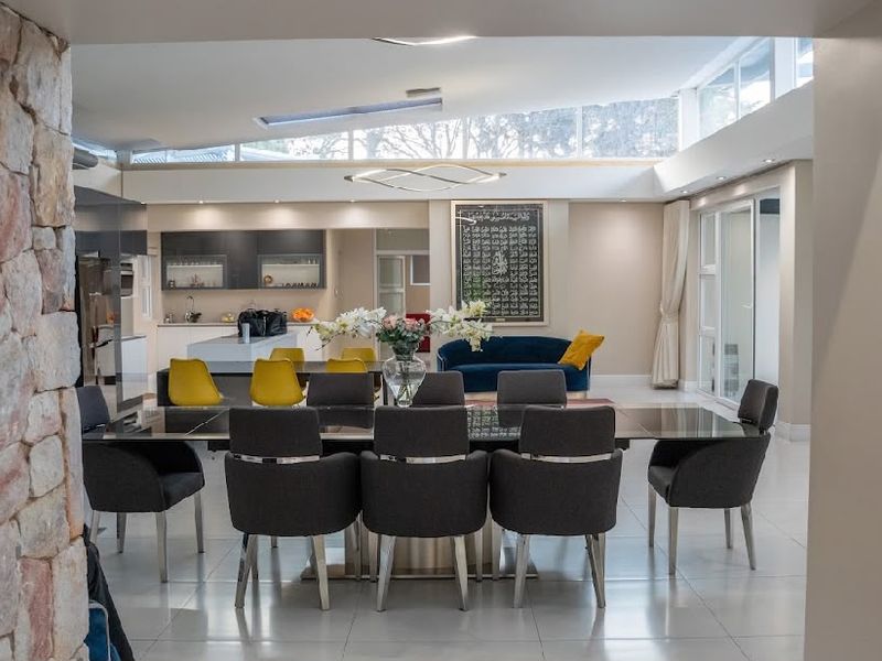 Spacious open-plan living and dining area featuring a stone accent wall, clerestory windows for natural light, and a modern kitchen with a central island.