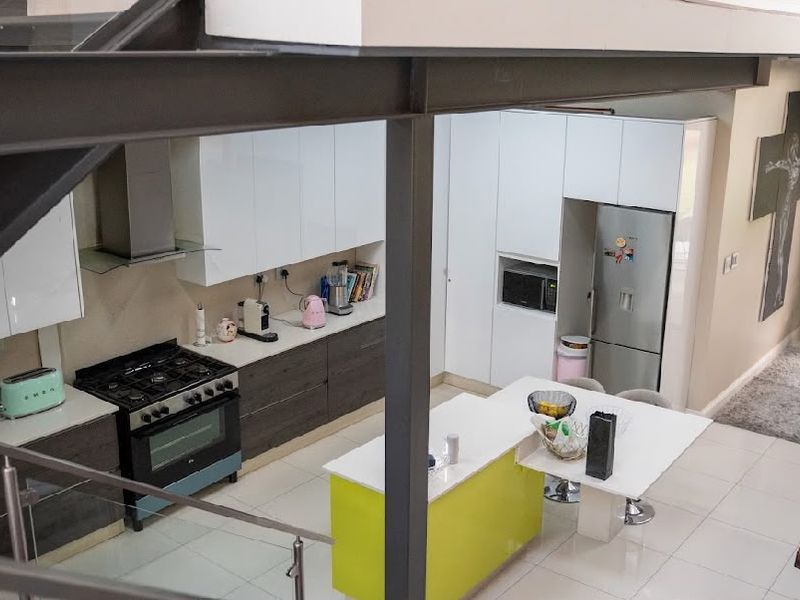 Modern open-plan kitchen featuring a central island, gas stove, and sleek cabinetry, seamlessly integrated with the living area under a mezzanine level.