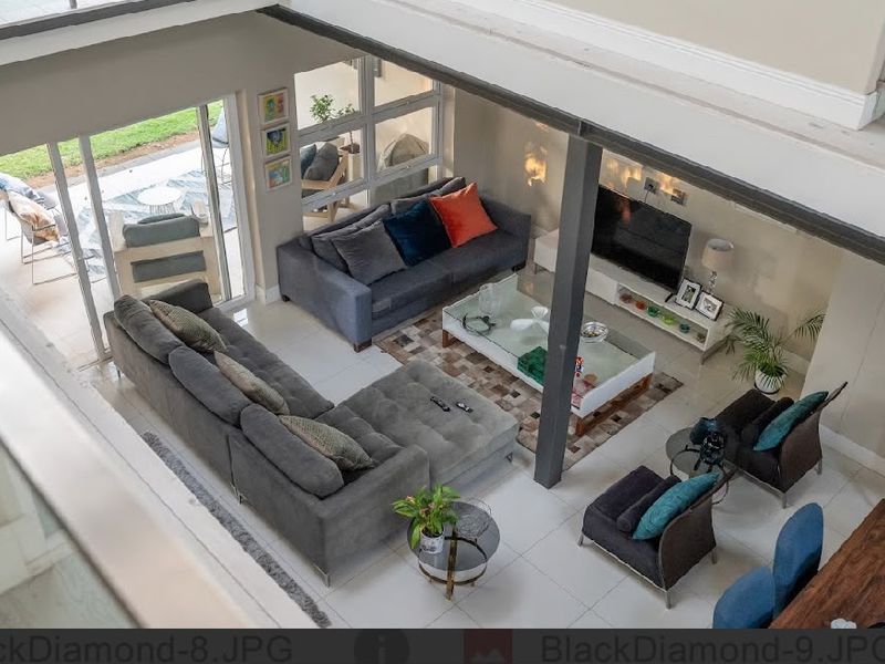 Spacious open-plan living area featuring tiled floors, a prominent steel support column, and large sliding glass doors leading to an outdoor patio.