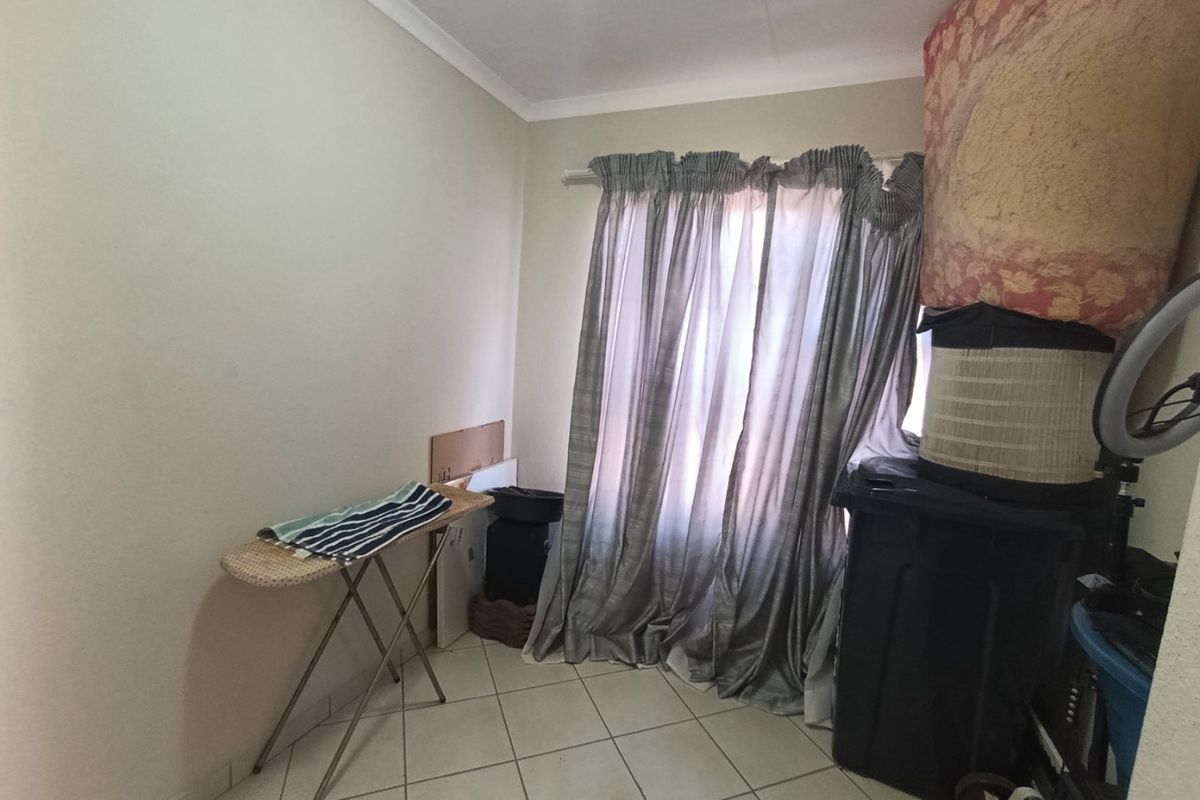 A small bedroom space featuring tiled flooring and cove cornicing, currently used for storage.