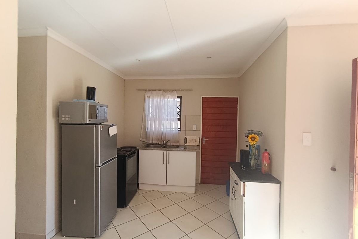 A functional kitchen area featuring tiled flooring, built-in cabinetry, a sink, and a stove, providing a practical space for meal preparation.