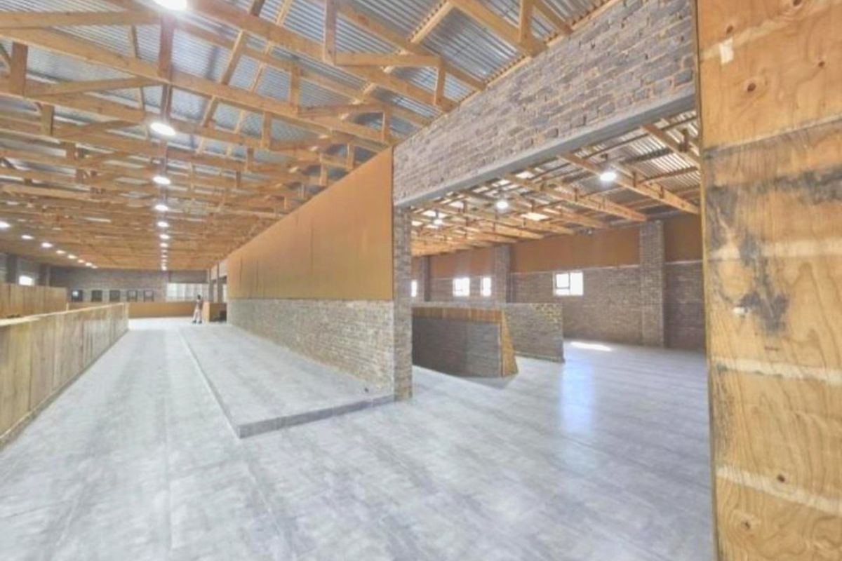 Spacious industrial-style utility area featuring exposed timber roof trusses, brick wall accents, and polished concrete flooring, suitable for various agricultural or commercial uses.