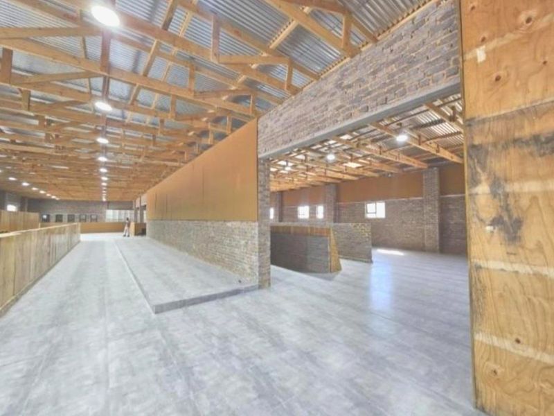 Spacious industrial-style utility area featuring exposed timber roof trusses, brick wall accents, and polished concrete flooring, suitable for various agricultural or commercial uses.