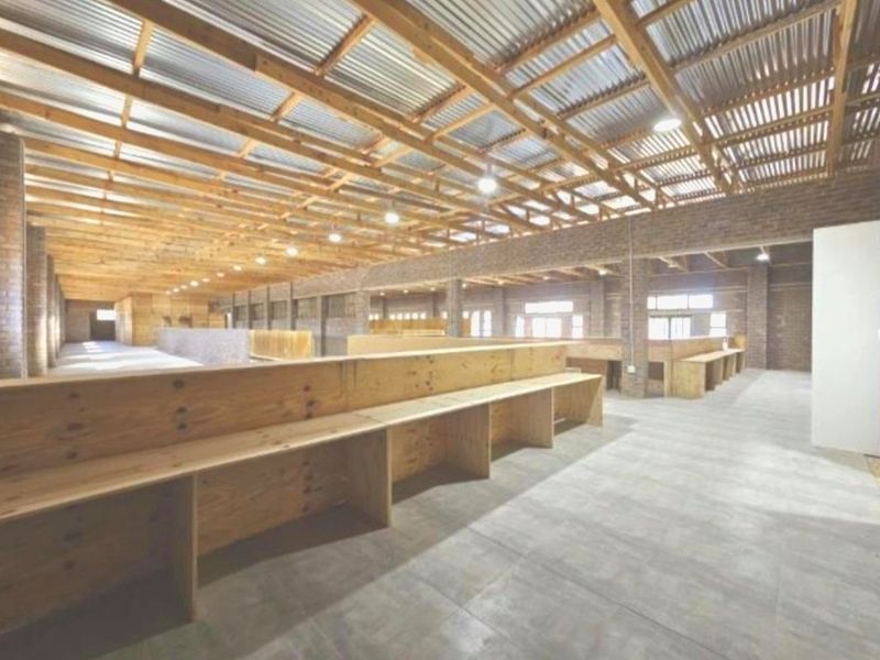 Spacious utility area featuring exposed timber roof trusses, corrugated metal ceiling, face brick walls, and extensive built-in timber counters on tiled flooring.