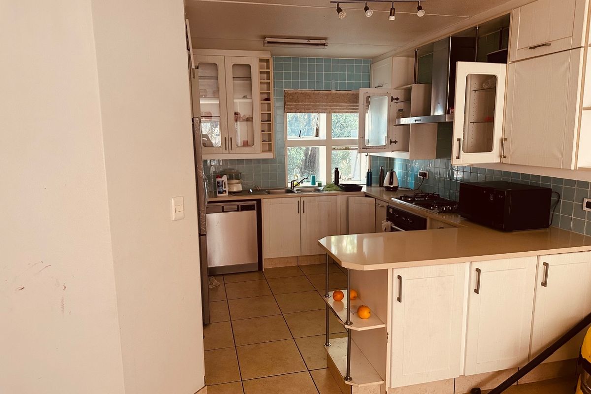 A functional kitchen featuring built-in cabinetry, a tiled backsplash, gas hob, and a breakfast counter, offering a practical layout with potential for modern updates.
