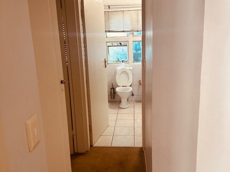 A view from a carpeted hallway looking into a bathroom featuring tiled floors and a toilet.