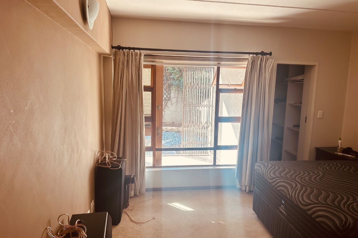 A bedroom featuring a built-in closet and a large window with access to an outdoor area, providing natural light and ventilation.