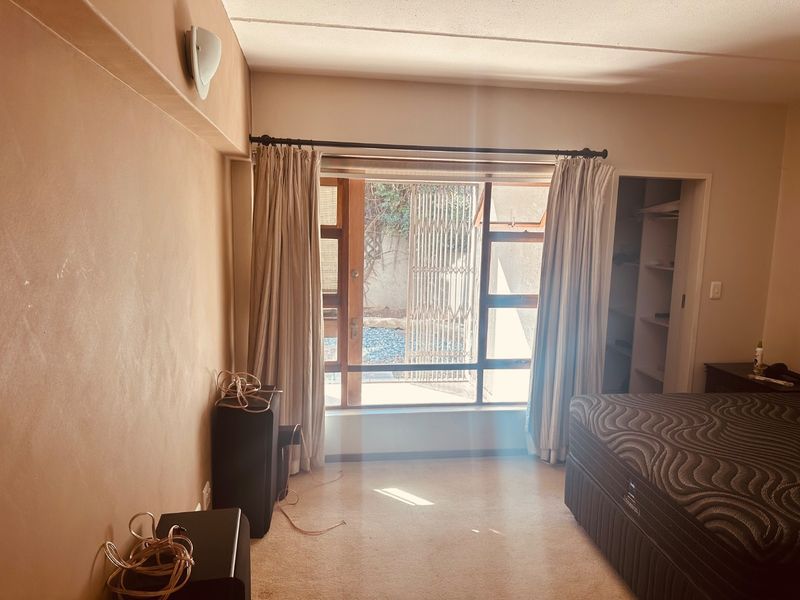 A bedroom featuring a built-in closet and a large window with access to an outdoor area, providing natural light and ventilation.