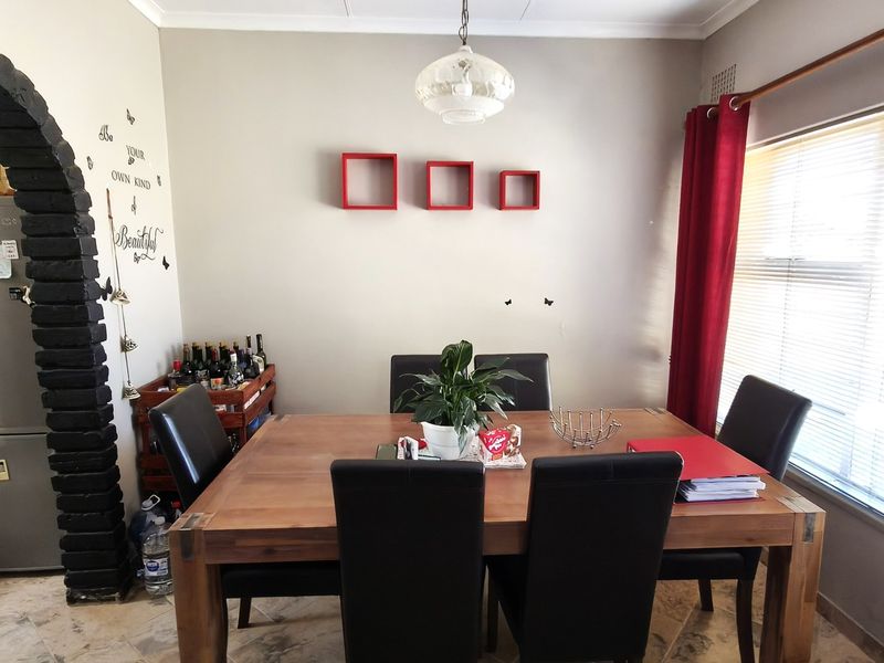 A dining room featuring a distinctive brick archway, tiled flooring, and a central pendant light fixture, providing a functional space for meals.