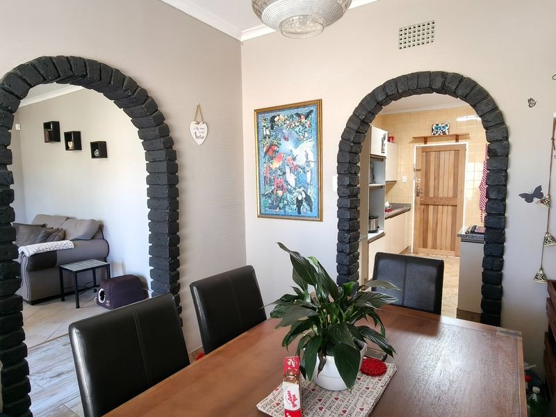 Dining area featuring distinctive dark brick archways connecting to the living room and kitchen, with neutral wall tones and tiled flooring throughout.