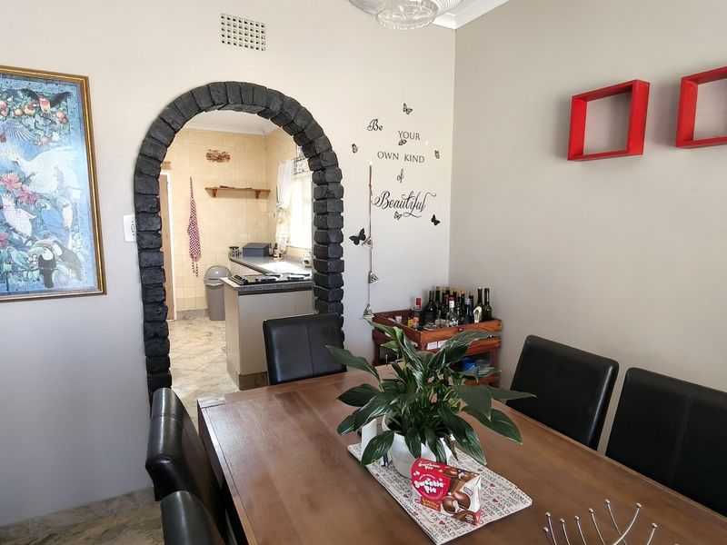 Dining room featuring a distinctive stone-clad archway leading to the kitchen, with neutral wall tones and tiled flooring throughout.