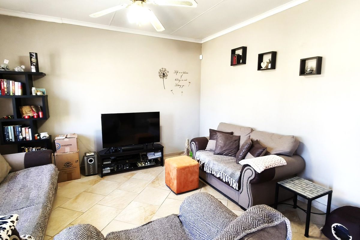 A comfortable living room featuring tiled flooring, a ceiling fan, and neutral wall finishes, providing a functional space for relaxation.