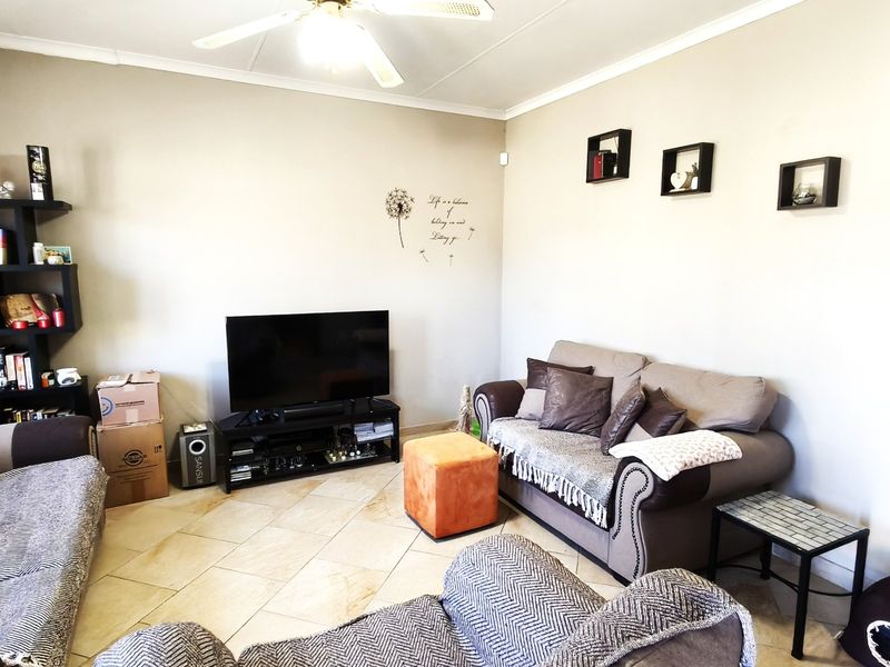 A comfortable living room featuring tiled flooring, a ceiling fan, and neutral wall finishes, providing a functional space for relaxation.