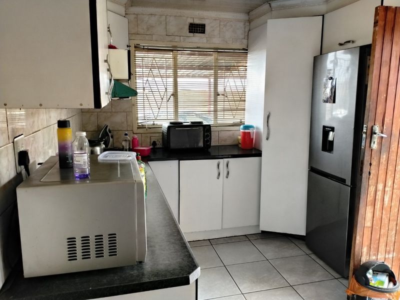 A functional kitchen featuring laminate countertops, tiled backsplash, and built-in cabinetry, offering a practical layout with potential for modern cosmetic updates.
