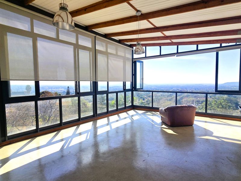 Spacious sunroom featuring polished concrete floors, exposed timber beams, a built-in fireplace, and expansive windows offering panoramic views.