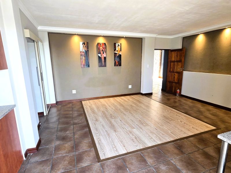 Spacious open-plan living area featuring a combination of ceramic tile and laminate flooring, recessed lighting, and direct access to kitchen cabinetry.