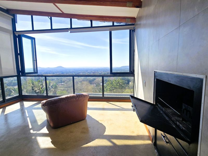 A bright living area featuring polished concrete floors, a built-in fireplace, and expansive windows offering panoramic views of the surrounding landscape.