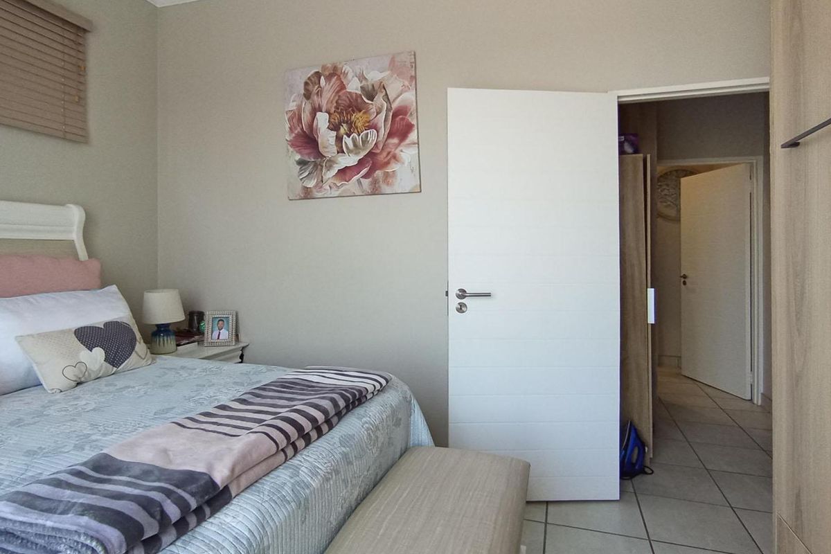 A well-maintained bedroom featuring tiled flooring, built-in wardrobe storage, and neutral wall finishes, providing a comfortable and functional living space.