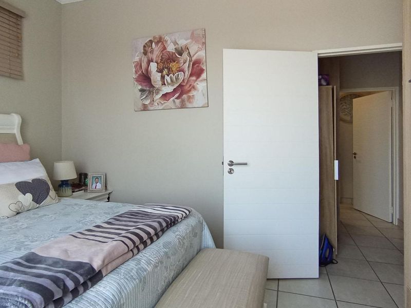 A well-maintained bedroom featuring tiled flooring, built-in wardrobe storage, and neutral wall finishes, providing a comfortable and functional living space.
