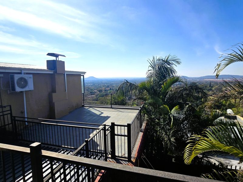 Spacious elevated balcony featuring tiled flooring, metal railings, and an expansive panoramic view of the surrounding landscape.